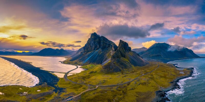 Aerial View of the Eystrahorn with Krossanesfjall Mountain and a nearby black sand beach in Iceland at sunset.