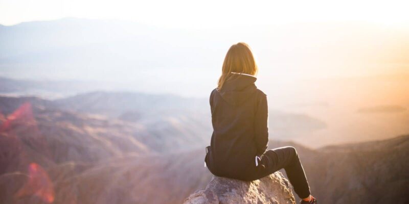 A girl sitting on top of mountain